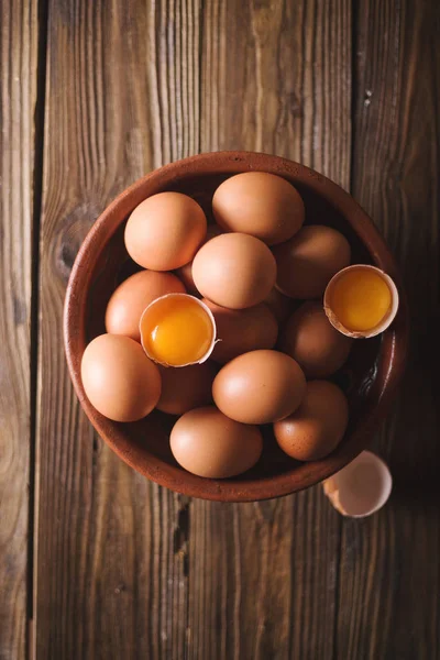 Kahverengi yumurta ve ahşap masa üzerinde kahverengi bir seramik kase kırık yumurta. Rustik tarzı. Yumurta. Un üzerinde ahşap bir masa dağıldı. Fotoğraf kavramı pişirme. Erişte, makarna. yumurta makarna — Stok fotoğraf