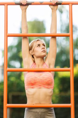 Kadının spor salonu çubuğunda yukarı kaldırarak yapması. Seksi genç fitness kız sokak spor jimnastik yukarı çeker. Sarışın fitness kadın sokak egzersiz karın egzersizleri yatay çubuk üzerinde performans üzerinde mükemmel fitness vücut ile spor giyim