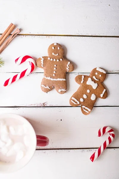 Vánoční pozadí. Muži perník a vánoční cukrové třtiny na bílém pozadí dřevěná — Stock fotografie