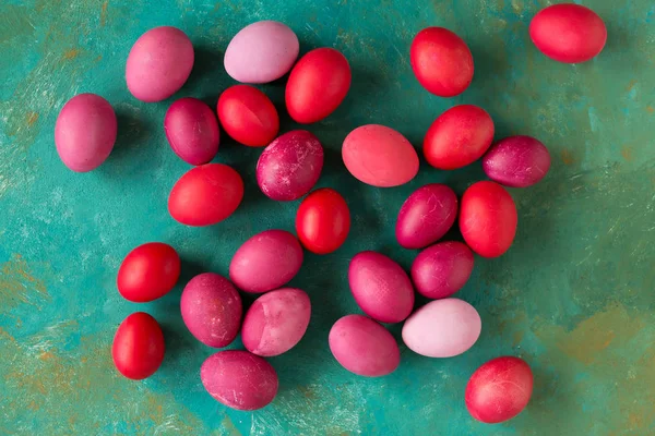 flat lay with pink and red Easter eggs on green background, top view