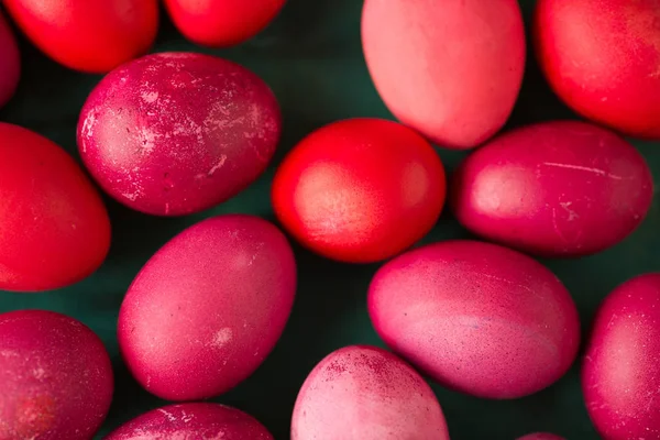 flat lay with pink and red Easter eggs on green background, top view