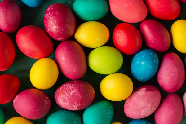 close up of multicolored Easter eggs on green table, top view