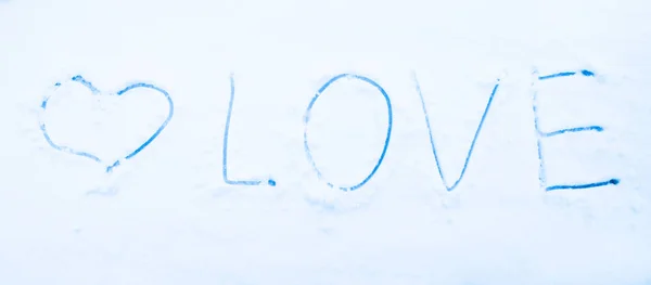 Heart shape and word LOVE drawn on pure white snow. Symbol of love.