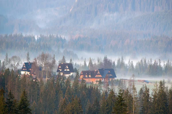 Mgła mglisty poranek nad dolina góra z drewniane gospodarstwo agroturystyczne dom budynki — Zdjęcie stockowe