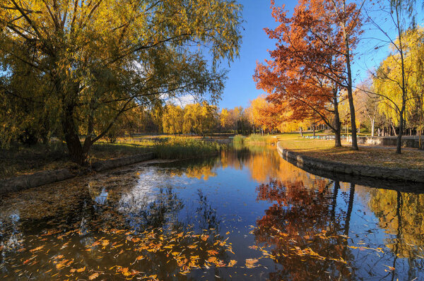 Beautiful autumn park with colorful trees reflected in the water.