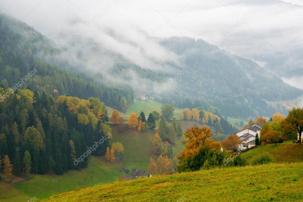 Amazing view of mountains in fog and colorful fall forest in Dolomite Alps, Italy