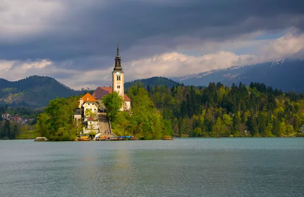 Lac de Bled et église de pèlerinage ensoleillé avec fond sombre — Photo