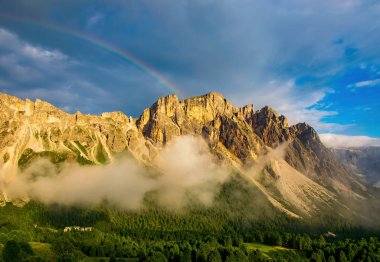 Ortisei ve St. Christina köyleri yakınlarındaki Puez-Odle dağ sırasının panoramik manzarası, Dolomitler, İtalya. Gökyüzünde güneşli dağlar ve gökkuşağı