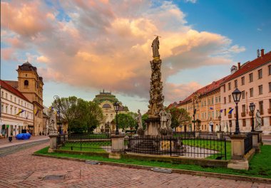 Heykel Immaculata ile Kosice 'deki ana meydanın göz kamaştırıcı manzarası - Veba Sütunu, eski binalar ve Slovakya Kutsal Üçlü Kilisesi, ilkbahar zamanı. Resimli günbatımı yanan gökyüzü