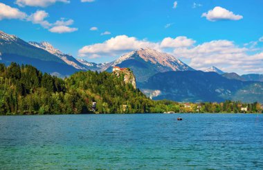 Doğal manzaralı Lake Bled - popüler turistik Julian Alps - castle rock ve arka plan üzerinde bulutlar tarafından bahar Slovenya kaplı dağları