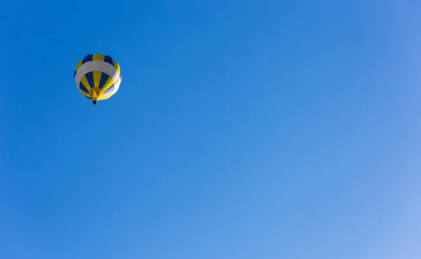 青空の中で孤独な飛行で黄色と青の熱気球 — ストック写真