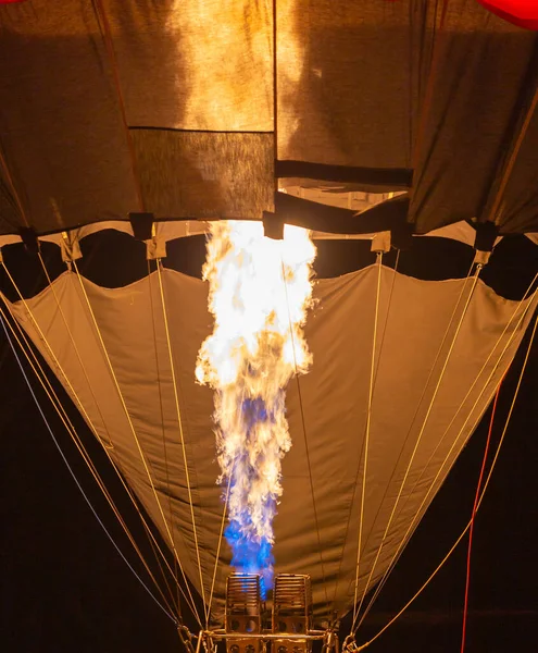 Hot air balloon burner lit to heat the air before departure.