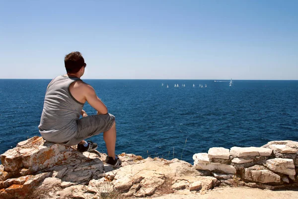 Adam denizde yelkenli tekneler izliyor — Stok fotoğraf