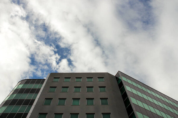 Architectural detail of modern office building. In the background is a beautiful sky with clouds.