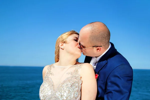 Pareja casada de pie y besándose al mar —  Fotos de Stock