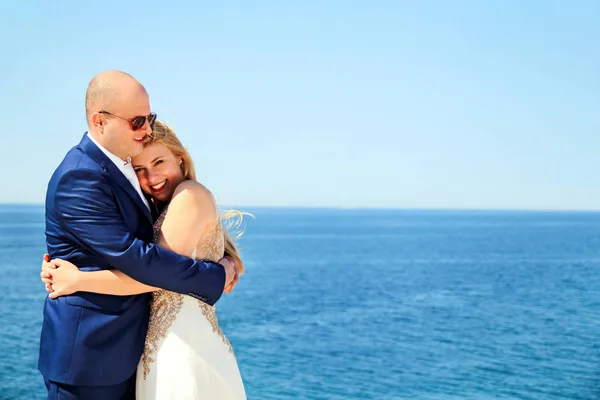 Hermosa pareja casada de pie y sonriendo junto al mar —  Fotos de Stock