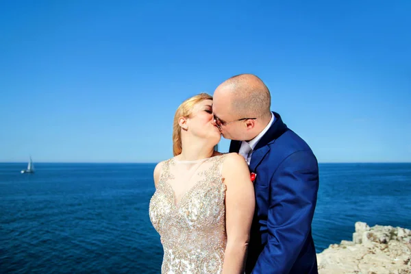 Pareja casada de pie y besándose al mar —  Fotos de Stock