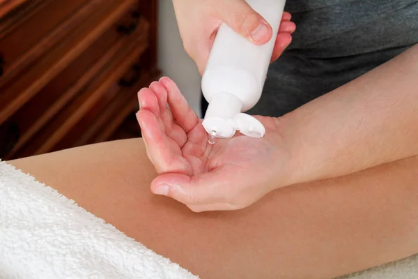 Men hands pump out of a bottle of massage oil — Stock Photo, Image