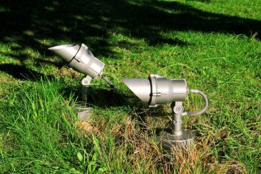 Projektör yeşil alanda, yakın çekim. Enerji tasarrufu açık projektörler, yeşil çim üzerinde küçük reflektörler. Işık organları. Bir yere spotlight yeşil bahçesinde. Lamba Led Park, Bahçe arka plan.