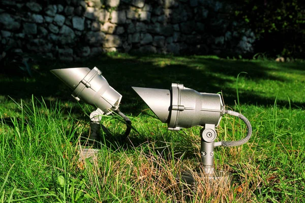 Projektör yeşil alanda, yakın çekim. Enerji tasarrufu açık projektörler, yeşil çim üzerinde küçük reflektörler. Işık organları. Bir yere spotlight yeşil bahçesinde. Lamba Led Park, Bahçe arka plan.