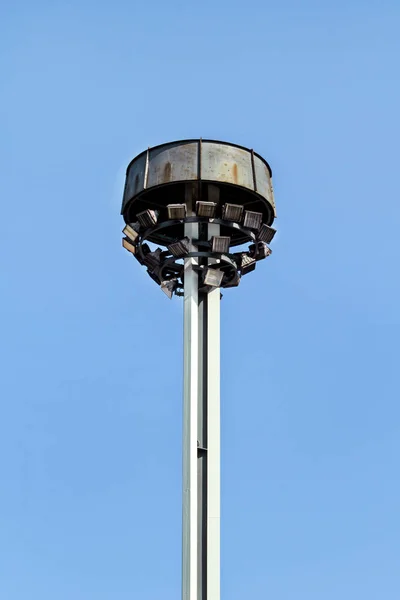 Tower with reflectors at the roundabout on the city road and street. Lighting pole with blue sky. Big lamp and light stadium poles or sports lighting. Flood light pole tower in the spotlight.