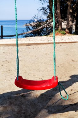Kırmızı plaj için salıncakta dinlendirici, mavi deniz arka plan üzerinde. Çocuk Bahçesi, güneşli, yaz saati boş zinciri hızıyla. Seyahat, güzel doğal çevre, Akdeniz, Adriyatik Denizi.