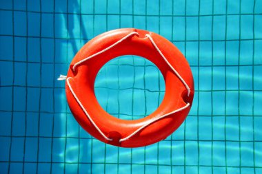 Kırmızı lifebuoy havuzu yüzük float, mavi Yüzme Havuzu yenileme içinde yüzen yüzük. Mavi su havuzunda yüzen kırmızı float. Güneşli yansımaları ile saf su üzerinde yüzen kırmızı şişme Yüzme yüzük.