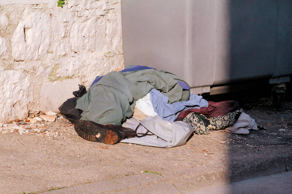 Overfilled trash dumpster near street. Old clothes and shoes waste left near to trash dumpsters on the street. Dirty refuse bins. Street scene. Recycling industry. Ecology. Not Ecology.