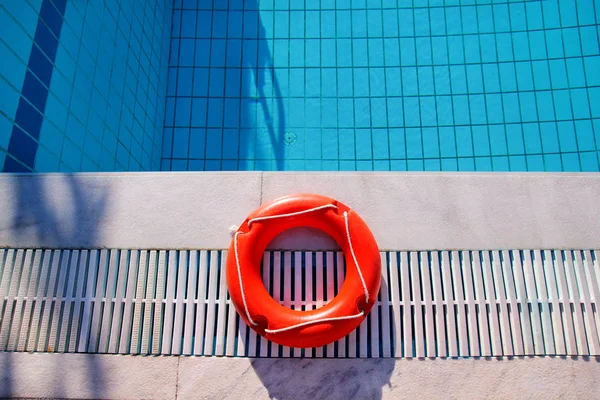 Red lifebuoy pool ring at swimming pool. Red pool ring in cool blue refreshing blue pool, room for your. Red pool ring and pool summer background. Summer, holiday, travel, swim, recreation, enjoyment.