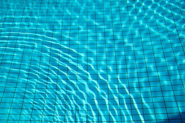 Azul rasgou a água na piscina. Piscina fundo cáustica ondulação e fluxo com fundo ondas. Luz clara ondas de água da piscina azul com reflexos do sol. Superfície da piscina azul . — Fotografia de Stock