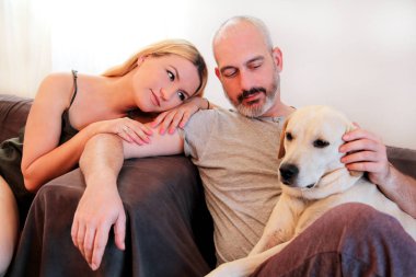 İnsanlar çift köpek vasıl ev ile. Sevgili mutlu ve sevimli yakışıklı bir çift ile onların sarı labrador retriever köpek vasıl ev oturma odası keyfini çıkarın. Güzel köpek, güzel köpek, güzel, pet, Evcil hayvan.