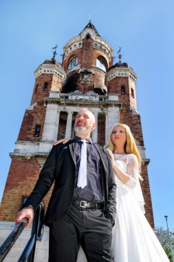 Düğün kavramı. Yakışıklı düğün birkaç güzel eski kilisenin önünde merdivenlerde duruyor. Kamera için poz güzel insanlar. Arka planda bina eski bir kale. Mutluluk.