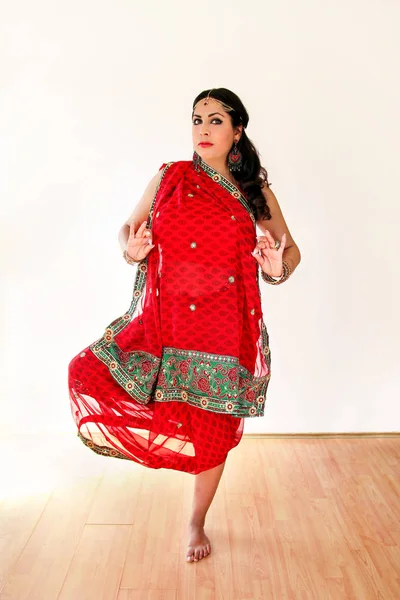 女性民族衣装でインド舞踊を踊っています。赤いヒンドゥー教サリー、インド舞踊の動きのホーンでハンサムな美しい少女の肖像画。伝統的な服でインド人のダンサー。ボリウッド ダンス。美容. — ストック写真