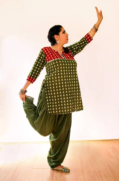 Woman dancing Indian dance in national dress. A beautiful girl portrait in shree kurta patiala set style, horn for the Indian dance movement. Indian dancer in traditional clothing. Bollywood dance.