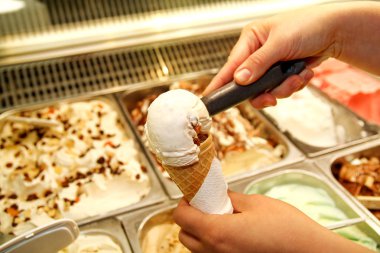 Kepçe ile el buzdolabı ve hizmet dondurma waffle koni içinde alır. Kadın alarak kepçe lezzetli dondurma. Buzdolabı dondurma ile. Kadın Dondurma dükkanında çalışıyor. Bir pastane. Tatlılar.