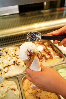 Kepçe ile el buzdolabı ve hizmet dondurma waffle koni içinde alır. Kadın alarak kepçe lezzetli dondurma. Buzdolabı dondurma ile. Kadın Dondurma dükkanında çalışıyor. Bir pastane. Tatlılar.