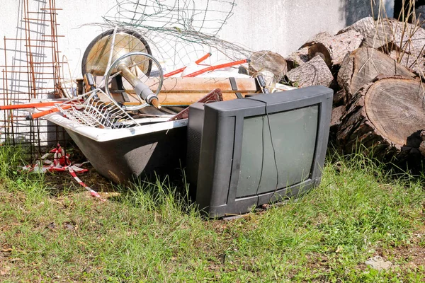 Old TV set dan sisanya dari sampah besar. TV lama dibuang di samping dinding dengan tumpukan sampah campuran. dalam lingkungan alam. Industri daur ulang. Bukan Ekologi. Ekologi. Bahan daur ulang dan limbah . — Stok Foto