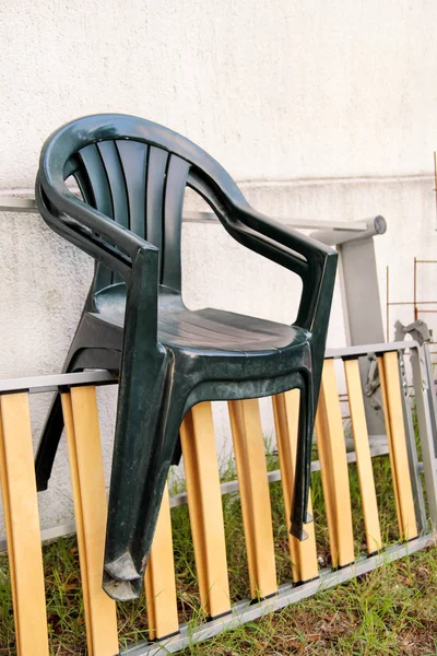 Cadeiras de jardim de plástico verde jogado fora e deixado em uma escada pela parede no jardim. Fundo de parede, natureza, móveis cadeira. Indústria de reciclagem, protecção do ambiente. material reciclado, resíduos . — Fotografia de Stock