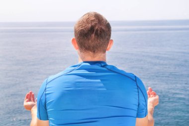 Bir sahil üzerinde Lotus olarak uygun bir adam. Açık havada Yoga yapan genç fitness erkek. Pratik yoga, meditasyon, pilates ve germe. Lotus pozisyonu yoga sınıfındaki yakışıklı sporcu.