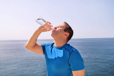 Sporcu eğitim sırasında bir mola verme taze temiz su bir Şişeden içme aittir ve arka plan bir güzel manzara doğa dışarıda ormanda ile temiz hava sahiptir. Sağlıklı yaşam tarzı.