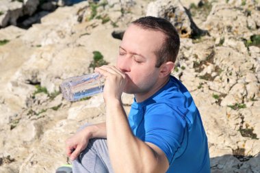 Sporcu eğitim sırasında bir mola verme taze temiz su bir Şişeden içme aittir ve arka plan bir güzel manzara doğa dışarıda ormanda ile temiz hava sahiptir. Sağlıklı yaşam tarzı.