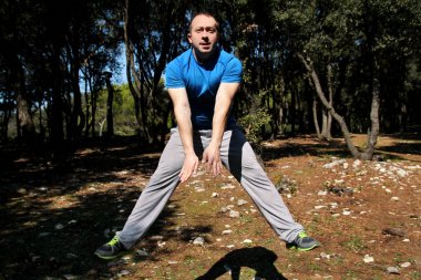 Kaslı adam ormandaki hava egzersiz egzersiz atlama yapıyor. Yakışıklı sporcu spor giyim giymek kadar açık havada doğa manzara hava alýþtýrmasýnda atlıyor. Uygun, sağlıklı yaşam konsepti çapraz.