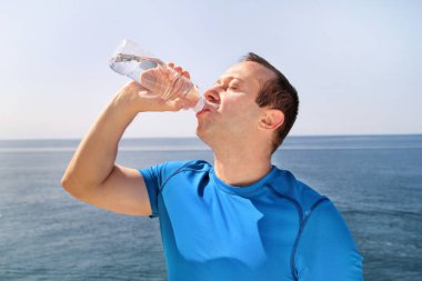 Sporcu eğitim sırasında bir mola verme taze temiz su bir Şişeden içme aittir ve arka plan bir güzel manzara doğa dışarıda ormanda ile temiz hava sahiptir. Sağlıklı yaşam tarzı.