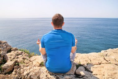 Bir sahil üzerinde Lotus olarak uygun bir adam. Açık havada Yoga yapan genç fitness erkek. Pratik yoga, meditasyon, pilates ve germe. Lotus pozisyonu yoga sınıfındaki yakışıklı sporcu.