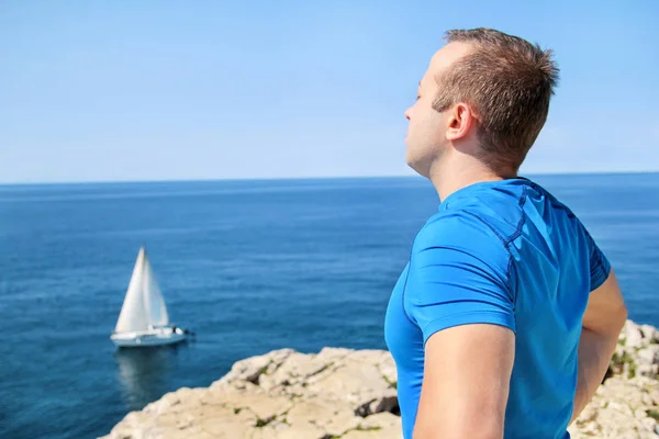 Bir spor giyim giymiş yakışıklı babası çalışan bir eğitimden sonra bir mola alır ve Adriyatik Denizi, arka planda yelken yelkenli ufku bakan güzel doğal çevre, sever. — Stok fotoğraf