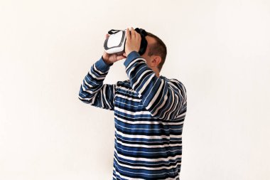 Giyen ve beyaz arka plan üzerinde aygıt sanal gerçeklik gözlükteki mobil oyun app oynamaya dostum. Adam eylem ve sanal kulaklık, Vr kutusunu kullanarak akıllı telefonla kullanabilir. Çağdaş teknoloji kavramı