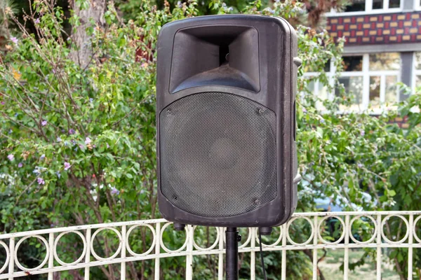 Black big speaker on stand outdoor / A big p.a. speaker on a stage at an outdoor music festival / Large audio speaker and equipment / Urban city street music concept.