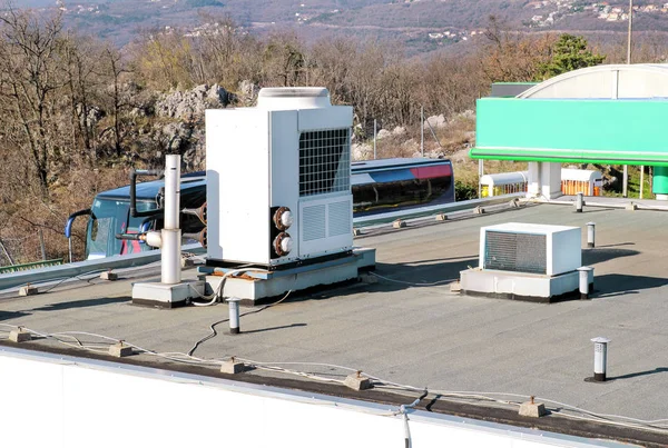 Air conditioning system assembled on top of a building / Air vents on top of commercial building / Air cooled water chillers top of roof / Outdoor climate unit and cooling and heating systems.