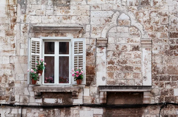 Aged windows and flower boxes of historical building from old town of Pula, Croatia / Detail of ancient venetian architecture with decorative elements / Material, texture, background and wallpaper.