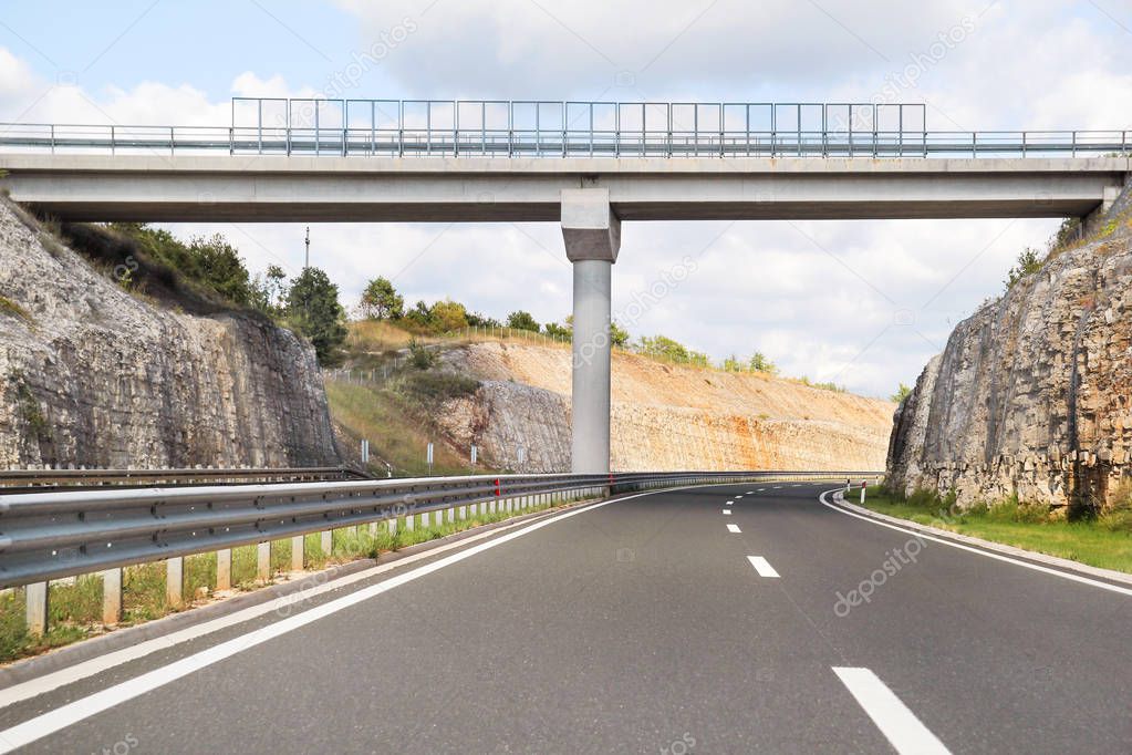 Scenic view on overpass and highway road leading through in Croatia, Europe / Beautiful natural environment, sky and clouds in background / Transport and traffic infrastructure / Signs and signaling.